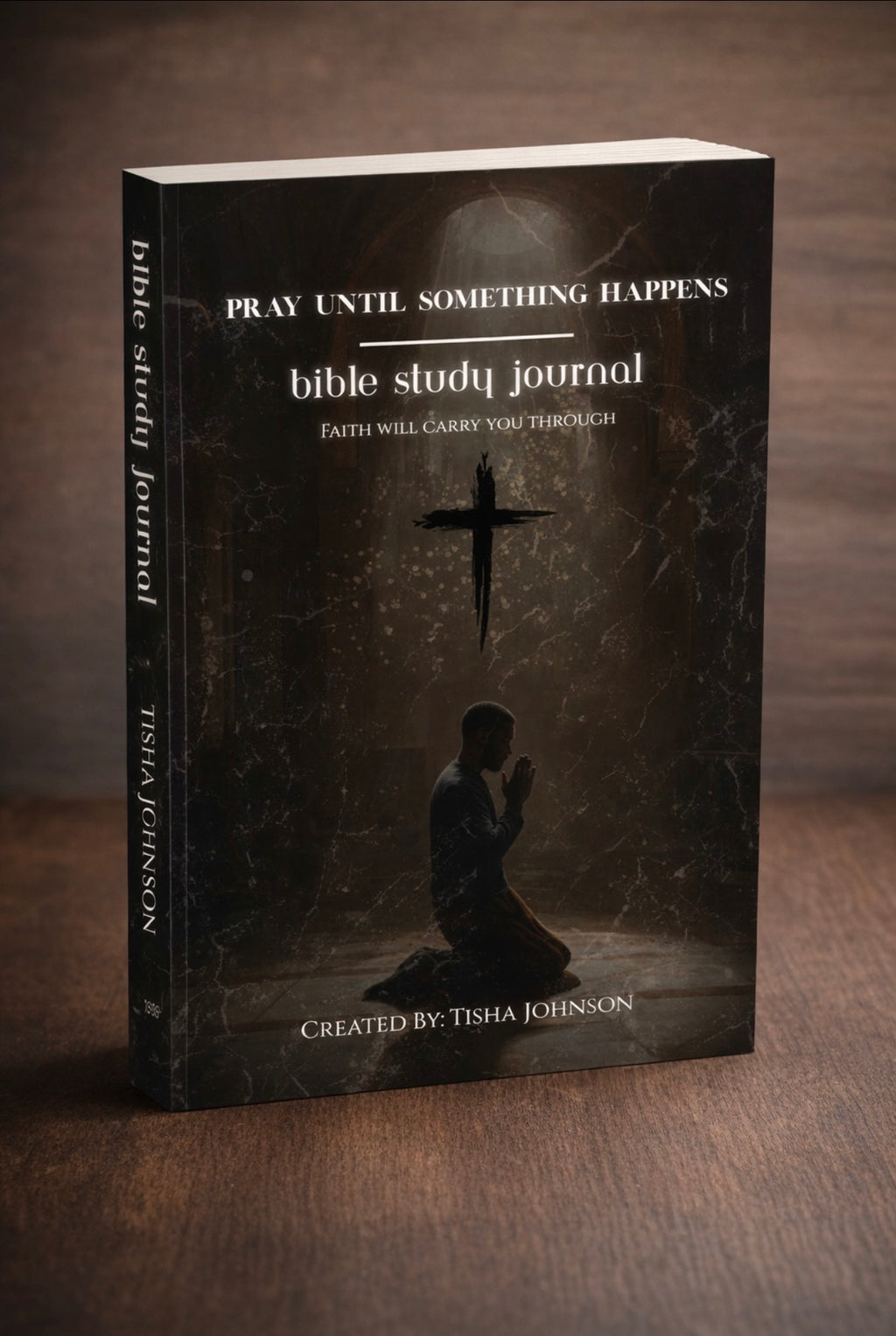 Bible study journal with a dark cover featuring a silhouette of a person praying and a cross.