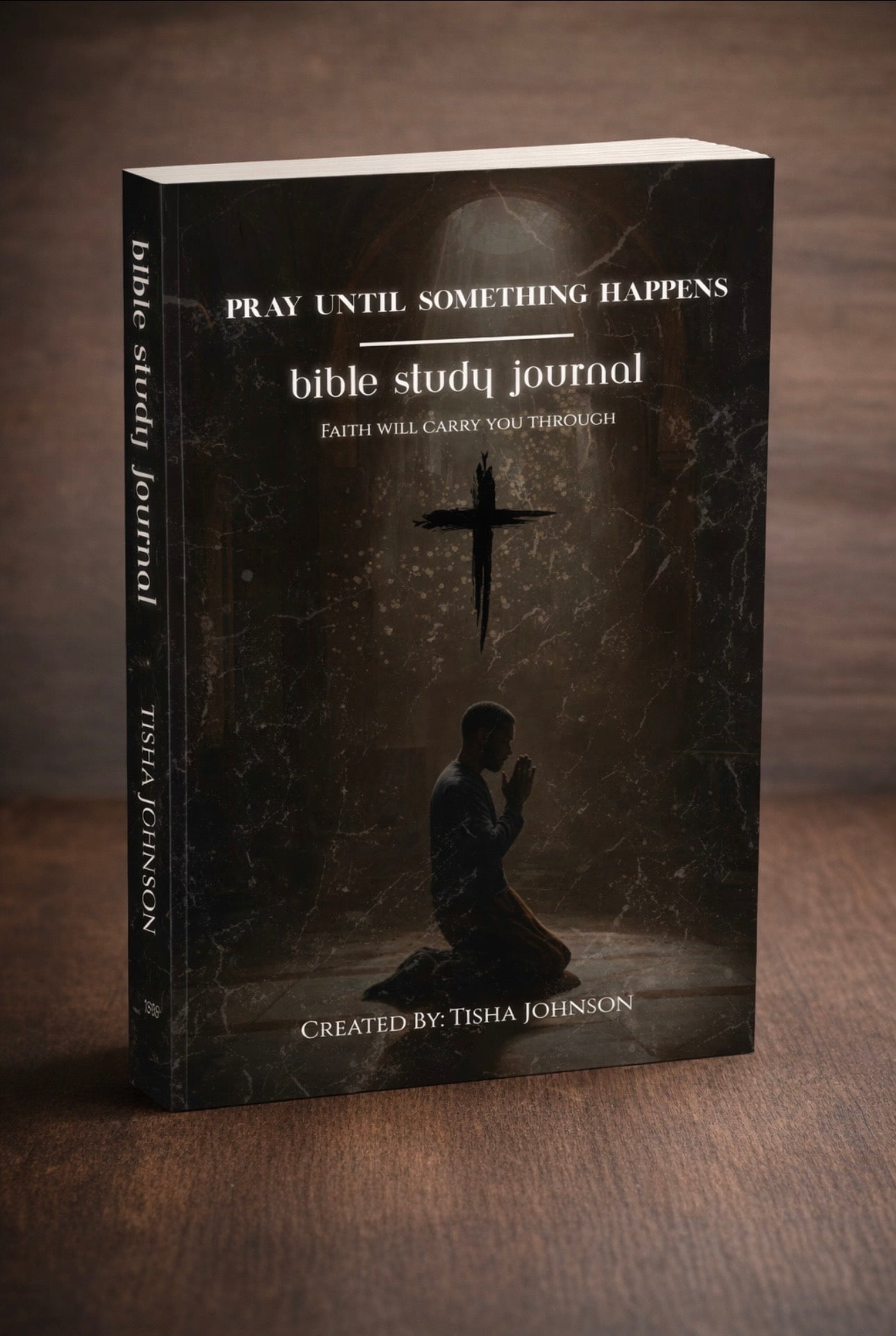 Bible study journal with a dark cover featuring a silhouette of a person praying and a cross.