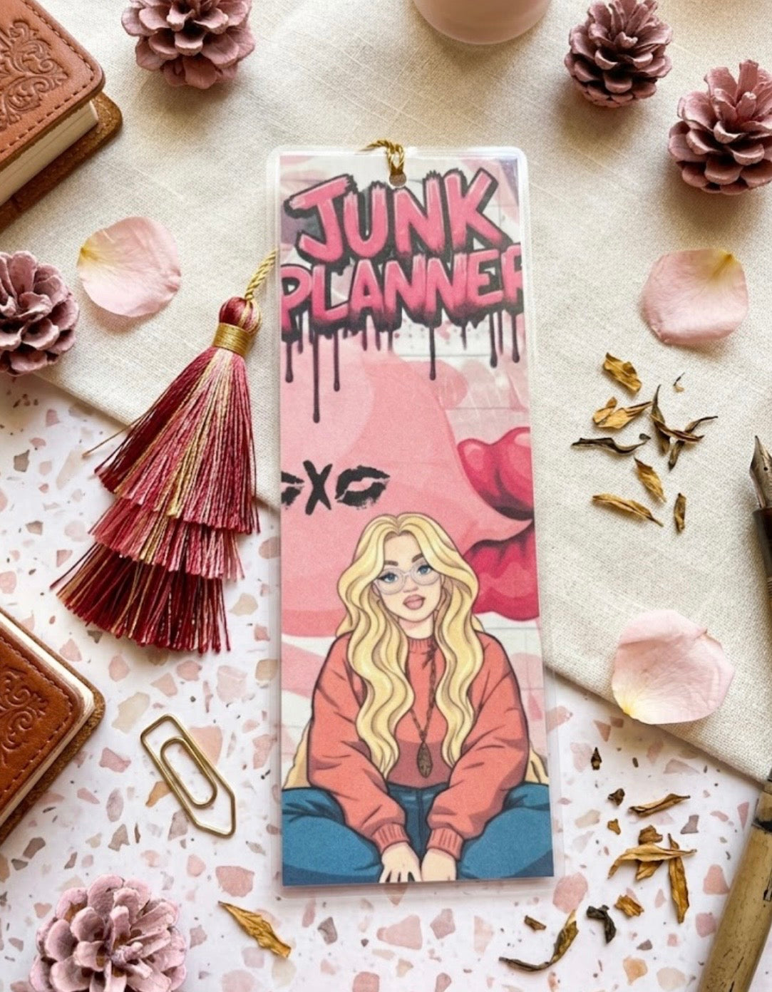 Bookmark with 'Junk Planner' design on a decorative surface with flowers and stationery items.