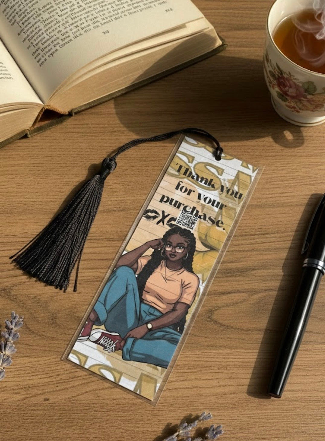 Bookmark with a person's illustration on a wooden surface with a book and tea cup.