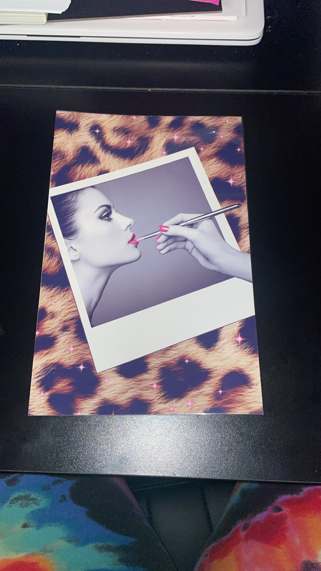 Polaroid-style photo of a woman's face with makeup application on a leopard print background.