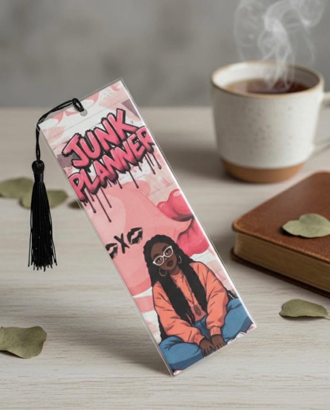Junk Planner product with a tassel on a table with a cup of coffee and notebook in the background