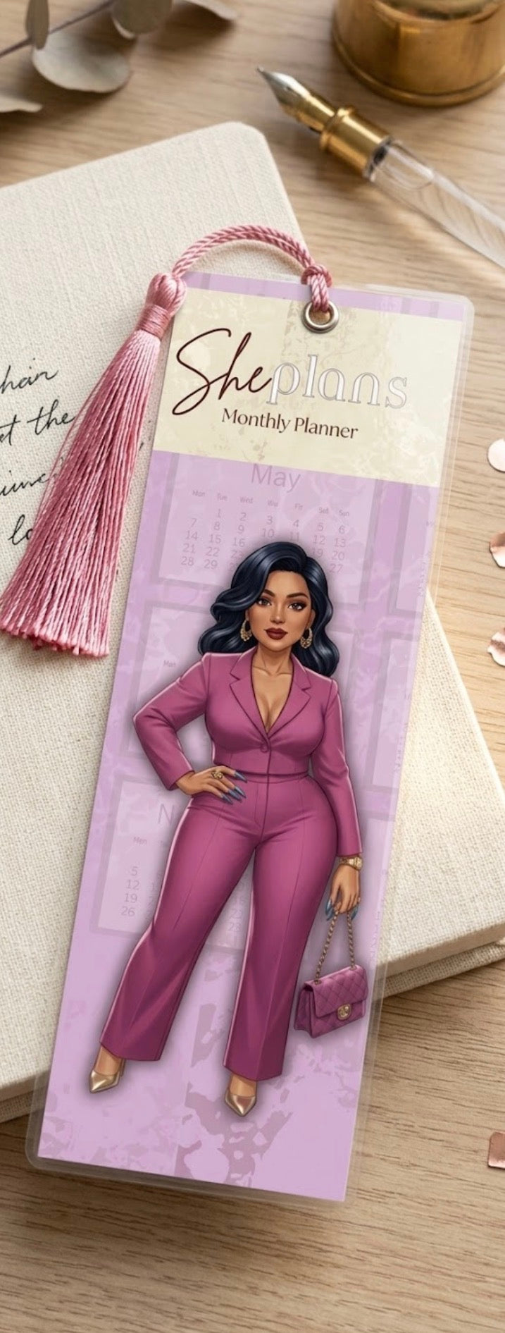 Bookmark with a woman in a pink suit on a purple background, placed on a wooden surface.