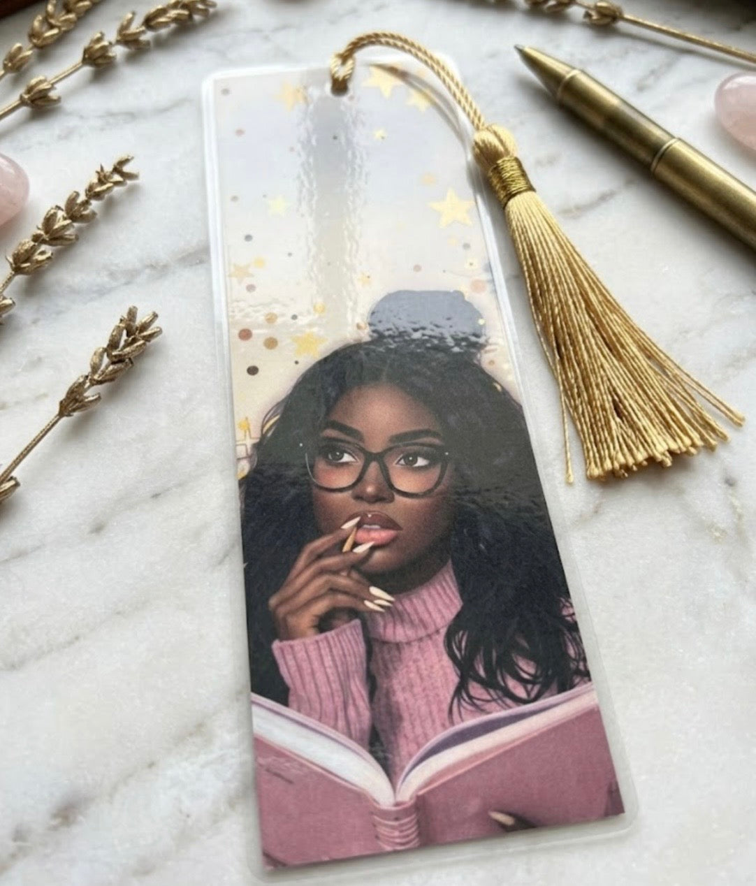 Bookmark with a design of a woman reading a book on a marble surface with decorative elements.