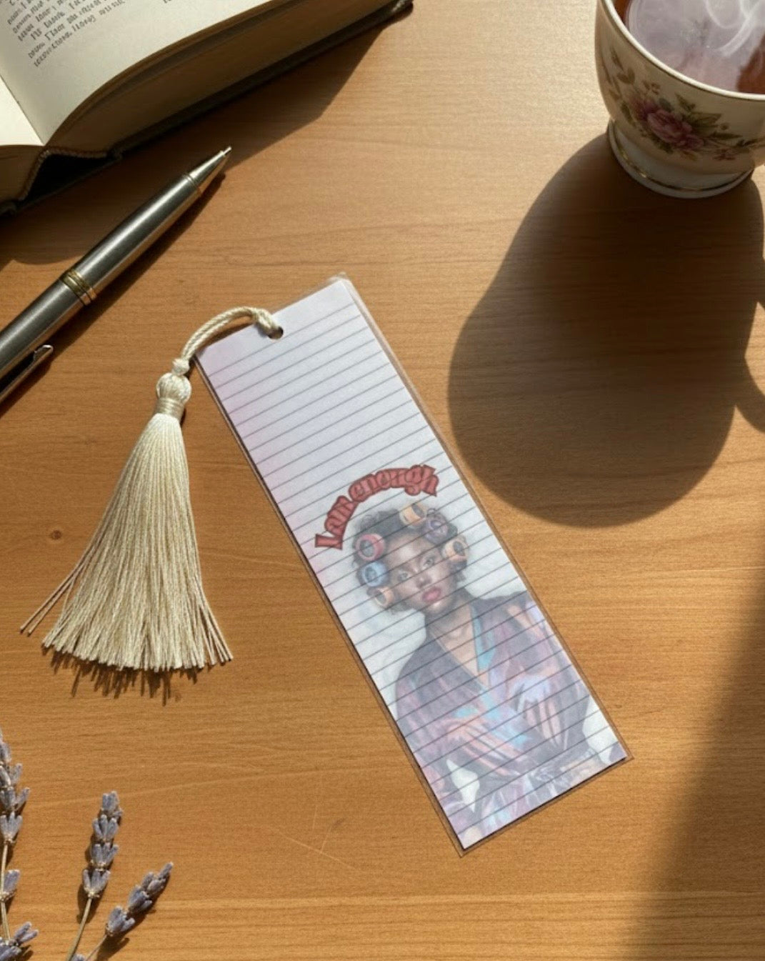 Bookmark with tassel on a wooden surface with a book and pen in the background
