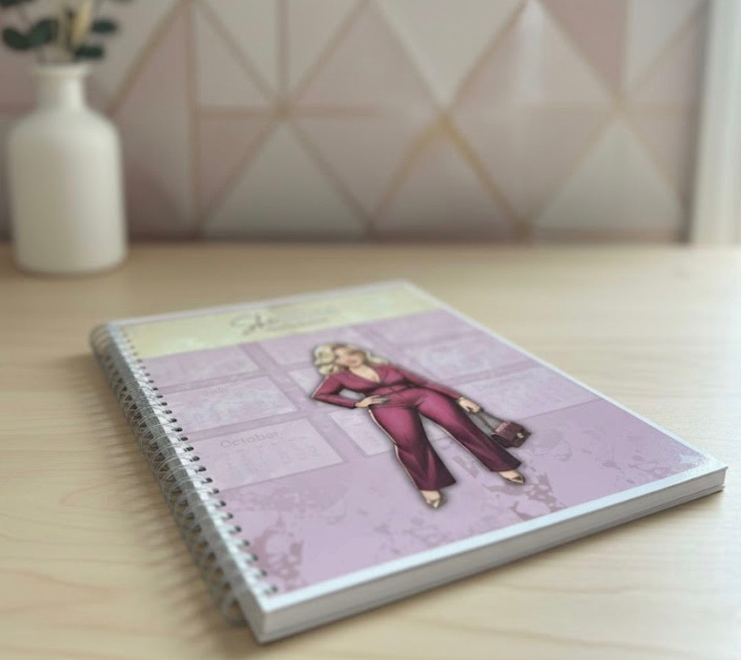 Planner with an illustration of a woman in a red outfit on a wooden surface.