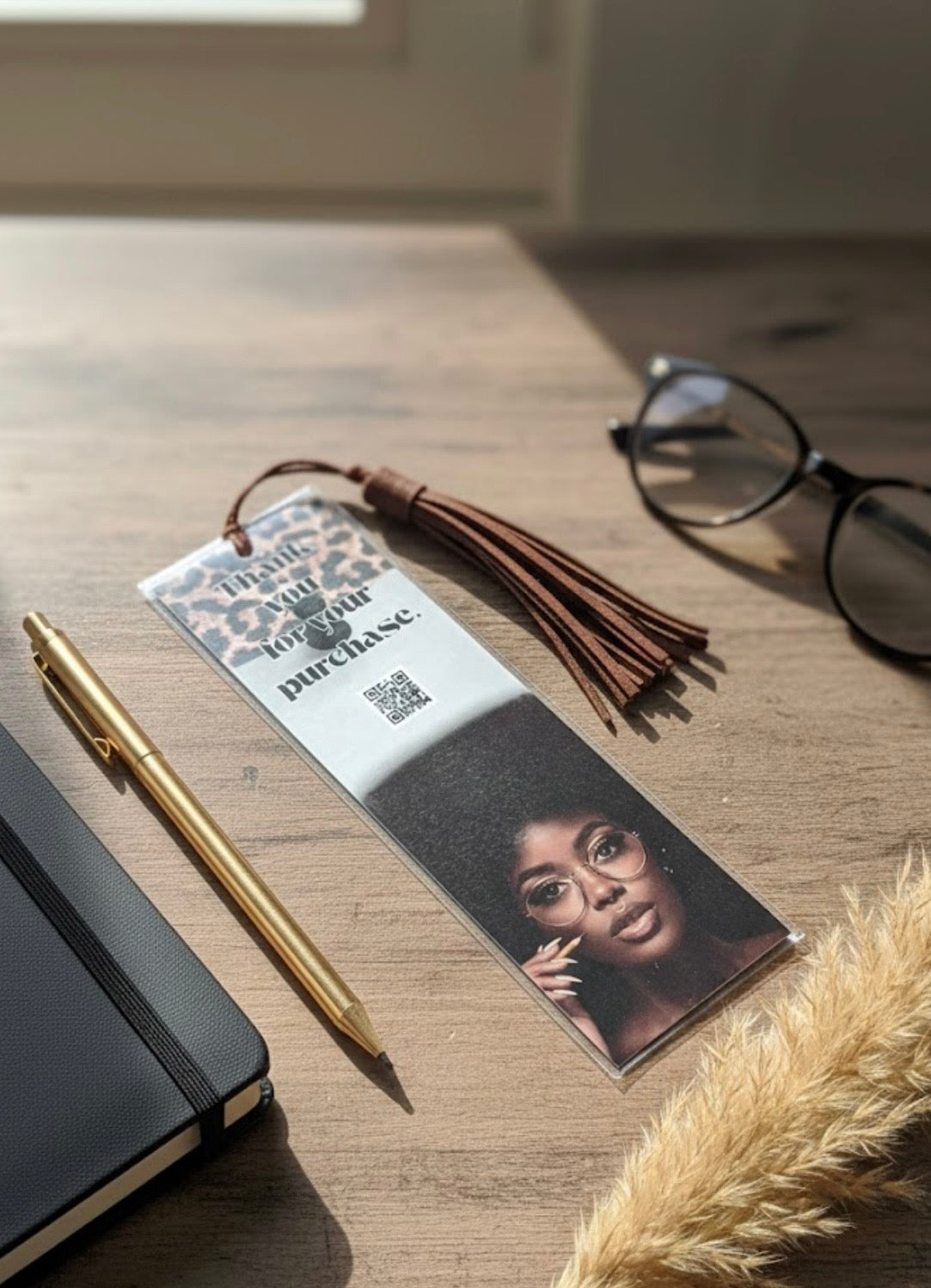 Bookmark with a photo of a person on a wooden surface with a pen and glasses.