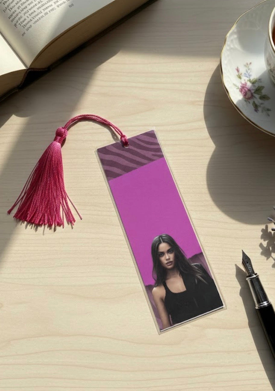 Bookmark with a purple background and a photo of a woman, placed on a wooden surface with a book and teacup in the background.